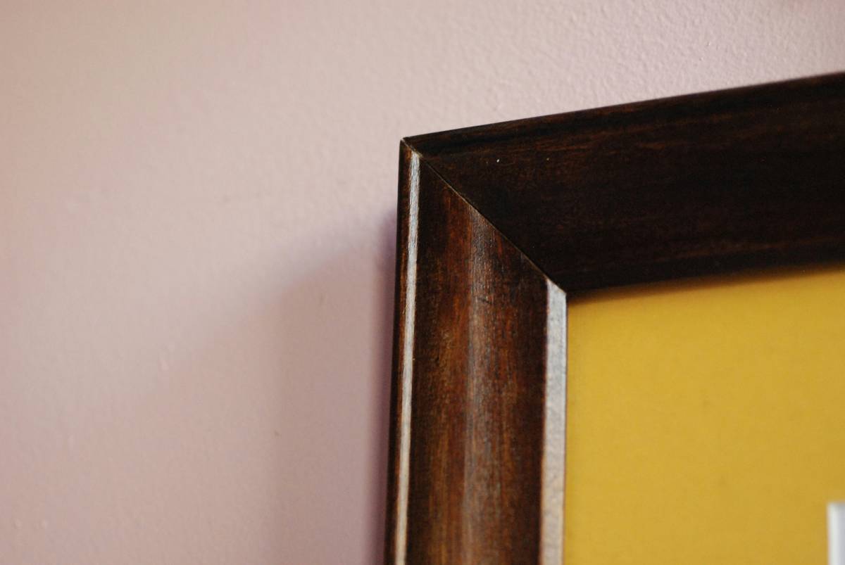 Elegant still life framed art hanging above a mid-century sideboard with complementary brass hardware